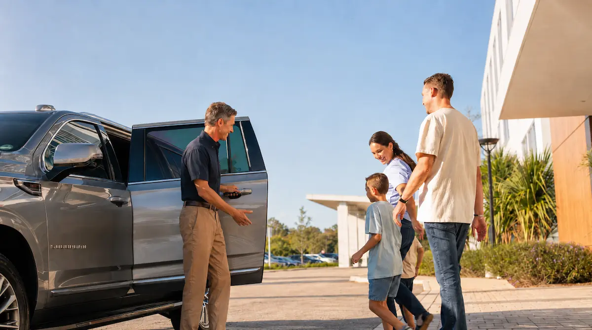Family approaching a luxury private vehicle with a professional chauffeur for a premium airport pickup at Orlando MCO by The Genie.